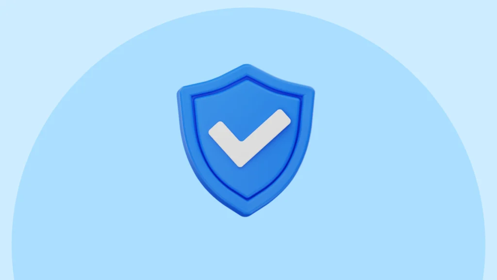 A blue shield icon with a white checkmark displayed in the center, set against a light blue circular background. The shield has a 3D appearance with layered depth, representing security, verification, or protection.